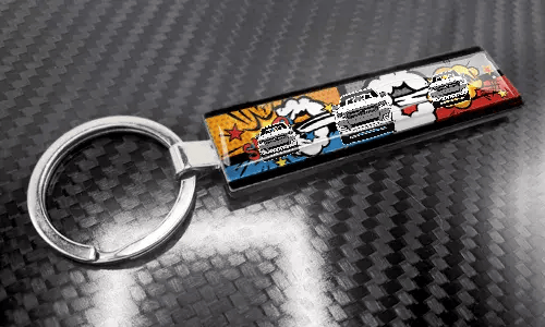 Szczupły brelok XL w stylu komiksowym z kolorową tablicą rejestracyjną na powierzchni o strukturze karbonu