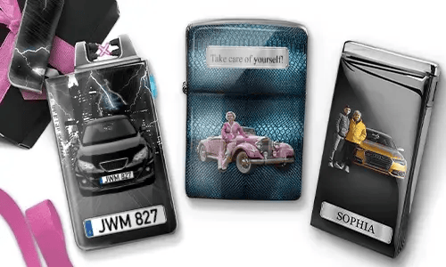 Three metal lighters featuring personalized designs. The left lighter shows a city skyline and a couple beside a car with 'BESTE OMA DER WELT'. The middle lighter depicts a pink vintage car with 'HAB DICH LIEB OMA' above. The right lighter displays a blue car and a license plate. Pink ribbons add a gift-like context.
