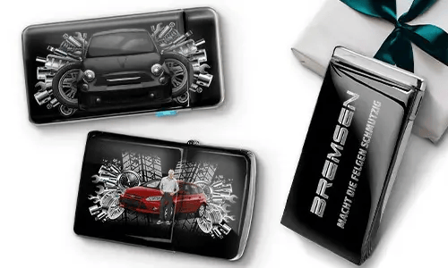 Drei elegante schwarze Geldbörsen mit Bildern von Autos und Zahnrädern, platziert neben einer Geschenkbox. Auf einer steht „Bremsen“. Das Design ist dynamisch und modern.