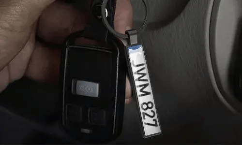 Llavero plateado de placa de matrícula cuelga de las llaves del coche dentro del vehículo