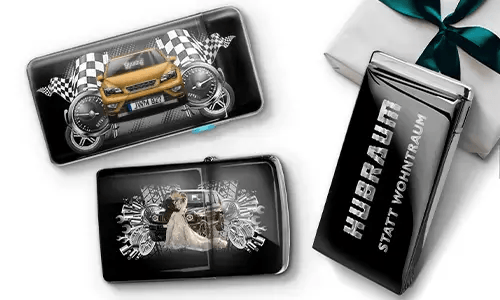 Three black wallets with car-themed designs and checkered flags, set against a white background. One shows a car with wheels, another features a couple, and one has 