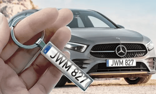 Portachiavi a forma di targa in stile fumetto, tenuto in mano con la targa dell’auto corrispondente sullo sfondo