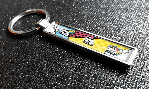 Comic-style license plate keychain with colorful pop-art car graphics on a textured surface