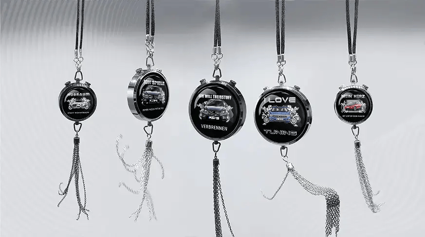 Five round keychains with German car-themed slogans and illustrations, hanging in a row